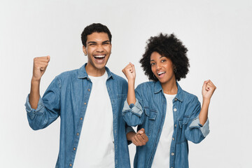 Happy couple two friends family girl guy of African American ethnicity wear denim casual clothes together do winner gesture celebrate clench fists say yes isolated on white color background