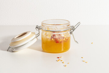 Open glass jar with hot honey on white background
