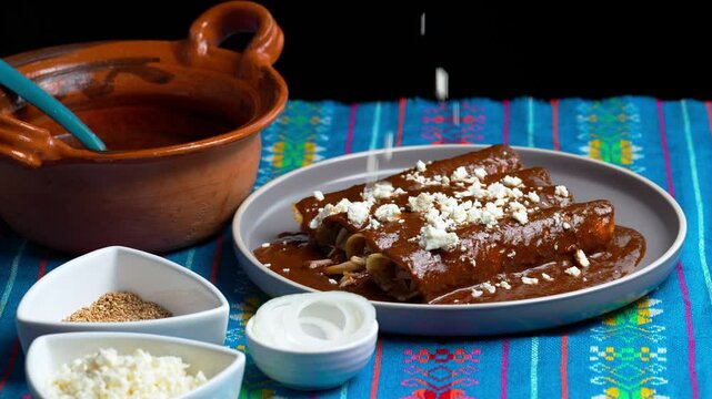 Mexican food, crumbled white cheese falling on a plate with chicken mole enchiladas or enmoladas