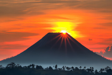 A stunning sunset with Batur volcano on Bali Island, Indonesia. Vibrant orange and purple hues illuminating the volcano and surrounding landscape.
