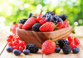 Bowl of mix of fresh fruits and berries on wooden table