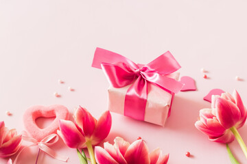 Pink tulips and hearts, gift box with ribbon on light pink background