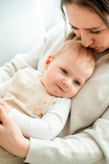 Happy mother holding her little son 9 months in her arms at home.