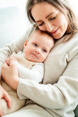 Happy mother holding her little son 9 months in her arms at home.