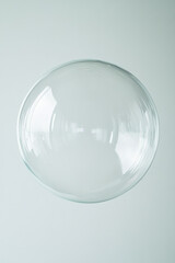 Transparent soap bubble on light background with reflections