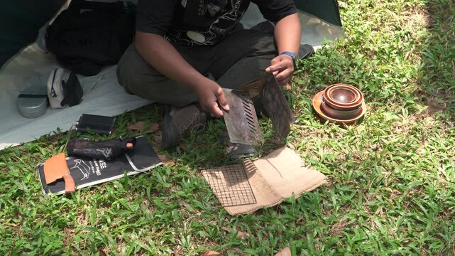 Close up of the activity of an Asian male adventurer cooking grilled shrimp using charcoal and wood. The bushcraft concept makes grilled shrimp with simple equipment in the lush wilderness