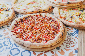 Hot tasty traditional various italian pizzas with salami, meat, cheese, onion, mushroom, tomatoes greens on a dark background