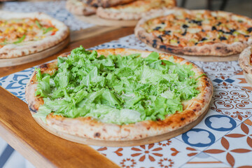 Hot tasty traditional various italian pizzas with salami, meat, cheese, onion, mushroom, tomatoes greens on a dark background