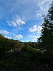 Scenic view of lush green mountains under a bright blue sky with fluffy clouds in the distance