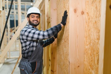 Modern modular house. Indian worker works on the construction of a wooden house