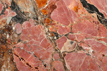 Fototapeta premium Intricate red marble texture with black and orange veins, showcasing a natural stone pattern.