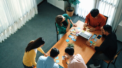 Top view of business team writing sticky notes while manager working on tablet and looking at analysis data. Group of diverse people sharing or exchanging marketing plan. Creative work. Convocation.
