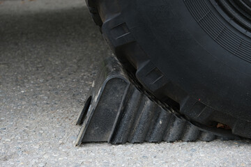 Wheel Chock under truck wheel, close-up. Plastic anti-rollback stop keeps the car stationary and prevents it from moving due to external influences. Trailer Car Tire Stopper.