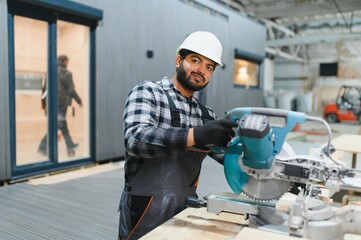 Fototapeta premium Indian Carpenter works with cutting boards on sawmills for the construction of wooden modular houses