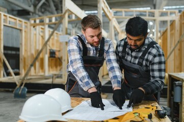 Fototapeta premium Two architects are looking at a construction plan drawing or blueprint. Construction process