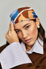 A beautiful woman elegantly poses with a headscarf, flaunting her fashionable style and confidence.
