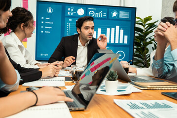Diverse group of business analyst team analyzing financial data report. Finance data analysis chart and graph dashboard show on TV screen in meeting room for strategic marketing planning. Habiliment