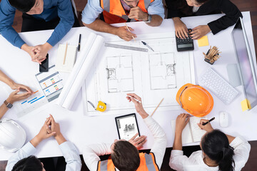 Top view banner of diverse group of civil engineer and client working together on architectural project, reviewing construction plan and building blueprint at meeting table. Prudent