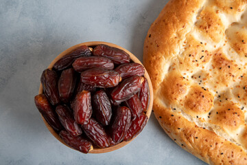 Dates fruit in a wooden bowl with pita bread on bright background