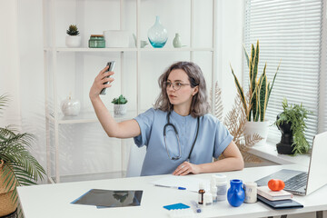 doctor at his desk broadcasting online to a social network or conducting an online patient appointment. doctor with a smartphone in his hands. concept of providing medical services online