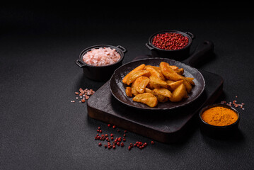Baked potato wedges with cheese and herbs on a dark background