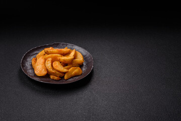 Baked potato wedges with cheese and herbs on a dark background