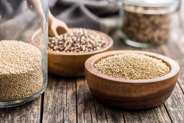 Mixed uncooked quinoa seeds in bowl on wooden table.