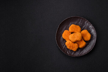 Delicious fresh crispy chicken nuggets on a dark concrete background
