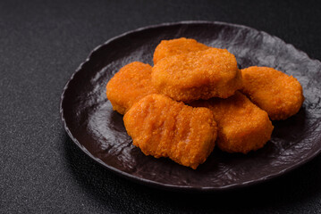 Delicious fresh crispy chicken nuggets on a dark concrete background