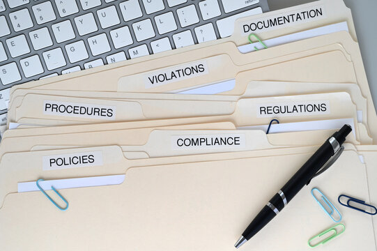 Compliance, Policies, Regulations, Violations, Procedures and Documentation folders on a desk