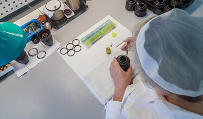 An engineer assembles a camera lens by hand.