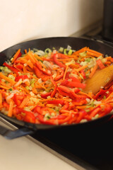 Stir frying chopped leek, carrots and red bell peppers in a wok. Selective focus.