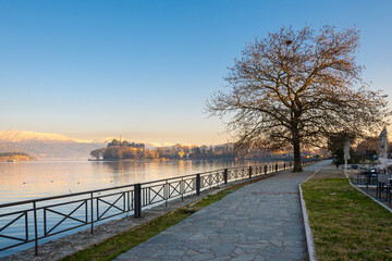 A stone path near to Ioannina lake in Greece. Snow covered mountains in the backgorund and the minaret of Aslan Pasha Mosque.