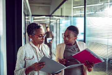 Business colleagues discussing project on tablet in office hallway