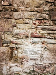 Background: Uneven old wall with different colored patched clinker bricks. Closeup. Walls of Edinburgh, Scotland, UK. Sandstone. Moss stains. Antique