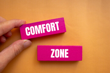 Comfort zone message written on pink wooden blocks with orange background. Conceptual comfort zone symbol. Copy space.