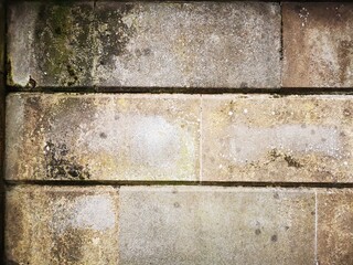 Background: Uneven old wall with different colored patched clinker bricks. Closeup. Walls of Edinburgh, Scotland, UK. Sandstone. Moss stains. Antique