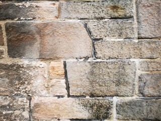 Background: Uneven old wall with different colored patched clinker bricks. Closeup. Walls of Edinburgh, Scotland, UK. Sandstone. Moss stains. Antique