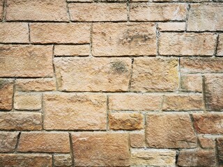 Background: Uneven old wall with different colored patched clinker bricks. Closeup. Walls of Edinburgh, Scotland, UK. Sandstone. Moss stains. Antique