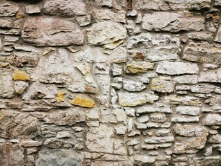 Background: Uneven old wall with different colored patched clinker bricks. Closeup. Walls of Edinburgh, Scotland, UK. Sandstone. Moss stains. Antique