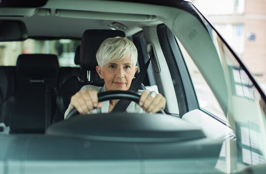 Senior businesswoman driving car confidently