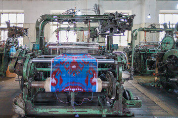 A loom with a carpet in the process of sewing.