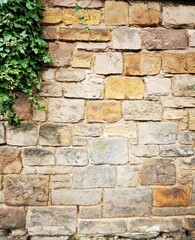 Background: Uneven old wall with different colored patched clinker bricks. Closeup. Walls of Edinburgh, Scotland, UK. Sandstone. Moss stains. Antique