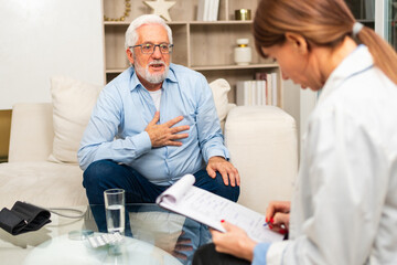 Obraz premium Female doctor examining older senior man in doctor office or at home. Old man patient and doctor have consultation in hospital room. Medicine healthcare medical checkup. Visit to doctor
