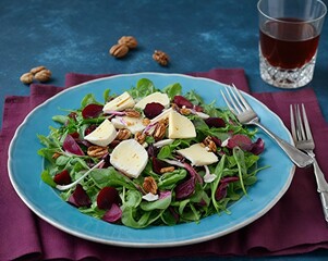 Arugula, Beet and cheese salad with fresh radicchio and walnuts on plate, dressing and spices on blue kitchen table background,