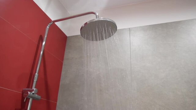 Water running from rain shower head in dark red modern luxury bathroom. SLO MO LD water flow from the rain shower head. Water flows from the shower head. 