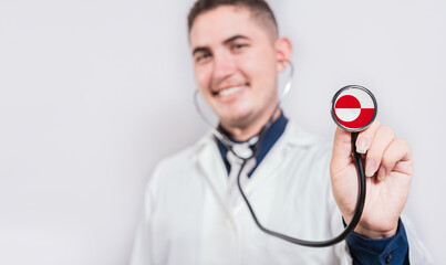 Happy doctor showing stethoscope with Greenland flag. Greenland National Healthcare concept