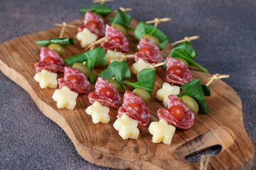 Canape with cherry tomatoes, sausage, cheese, spinach and olives
