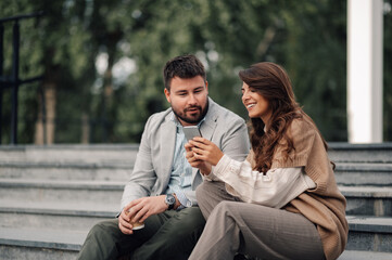 Two business colleagues enjoying a break and sharing content on smartphone