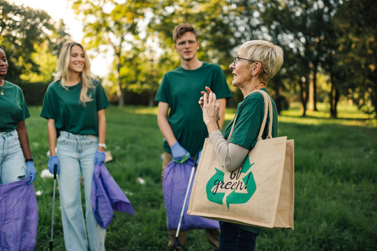 Group of volunteers discussing while picking up trash in park